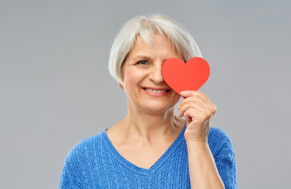 A woman holds up a heart symbol, signifying the importance of heart health during National Cholesterol Education Month. Discover how Senior Healthcare Advisors can guide you to better health through Medicare Advantage.