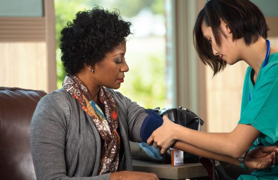 A woman undergoing a blood pressure check by a nurse, highlighting health monitoring through her Medicare Advantage plan.